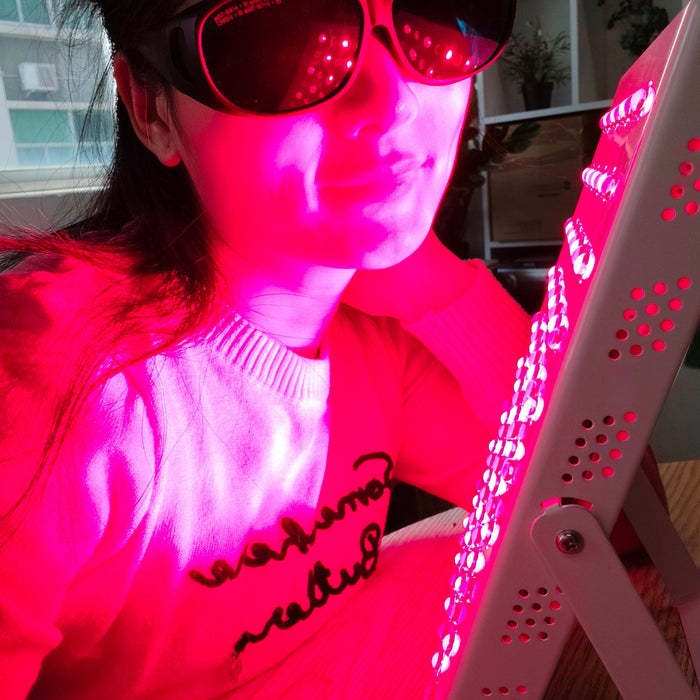 woman using red light therapy panel at home